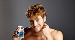 Cologne, face and product with man in studio with spray bottle for aroma, fragrance or fresh smell. Perfume, satisfaction ad smile of happy person on gray background for essence scent in glass