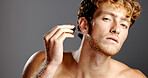 Face, beard oil and man with skincare, cosmetics and dermatology on gray studio background. Portrait, happy person and model with treatment, beauty and serum product in pipette for hydration and glow