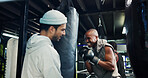 Active, men and personal trainer in gym, punching bag or practice for competition, sport and boxing. Power, fighter and training with instructor for performance, athlete and workout in fitness center