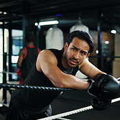 Sport, boxing ring and tired man on rope for relax, rest and health ...