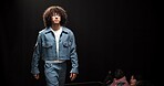 Man, model and walking on catwalk with fashion, confidence or showcase with audience. Style, glasses or person in spotlight at black background space with designer clothing, brand ambassador or event