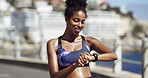Fitness, woman and check watch in city for running speed, exercise results or cardio performance. Sweating, african person or happy with timer for tracking workout, app notification or wellness stats