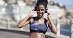 African woman, headphones and fitness in city for audio, listening to music and exercise podcast. Smile, person and streaming album for rest, workout playlist and sports training of marathon practice
