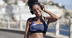 Active, woman and headphones for fitness in city for audio, listening to music and exercise podcast. African person, streaming and good mood, workout playlist and sports training of marathon practice