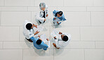 Doctor, medical team and meeting with documents for healthcare development or mission above. Top view, group or health employees with paperwork in huddle for progress or performance at hospital