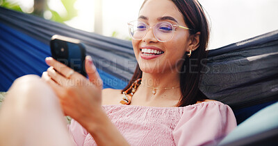 Buy stock photo Woman, hammock and phone on holiday outdoor with glasses for reading, social media or meme. Relax, happy and person with technology for connection, vacation or online review at resort in summer
