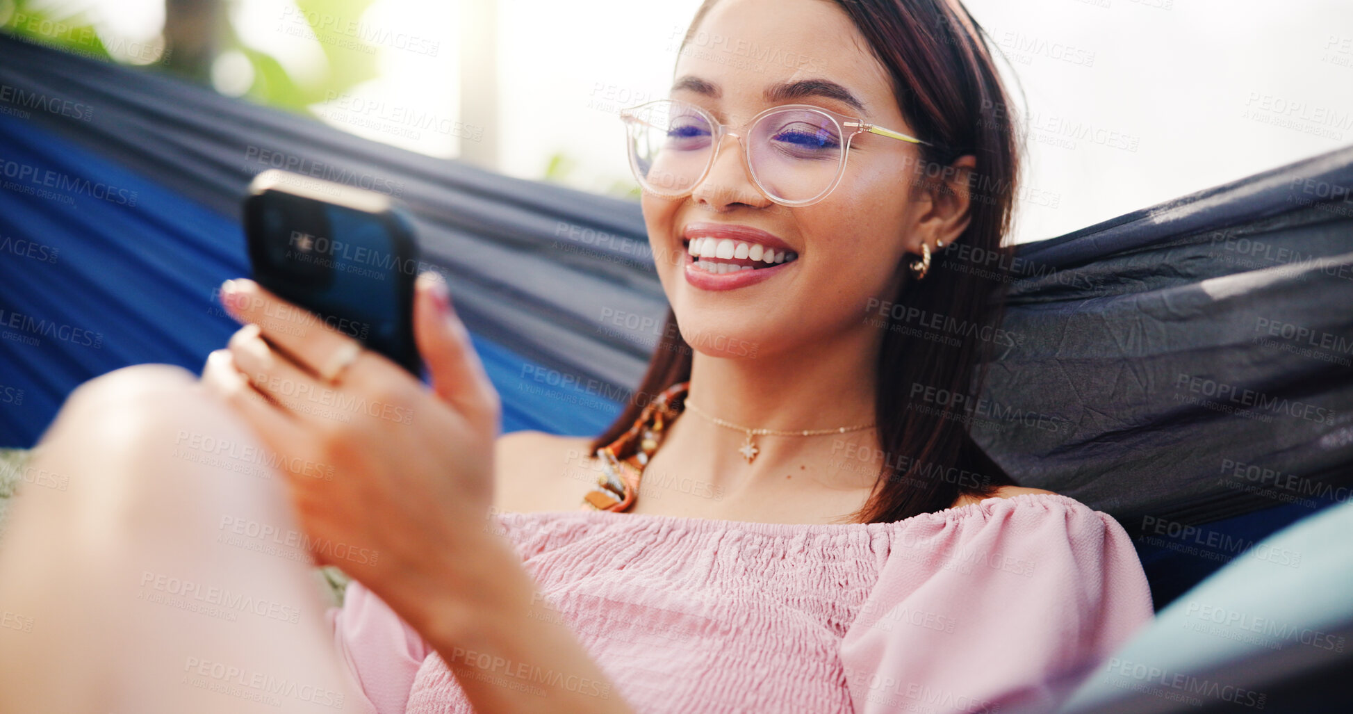 Buy stock photo Woman, hammock and phone on holiday outdoor with glasses for reading, social media or meme. Relax, happy and person with technology for connection, vacation or online review at resort in summer
