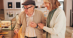 Elderly couple, cafe and choice for cake by display with smile, date and excited at coffee shop. Senior people, man and woman with decision, dessert and happy with love for pastry sale at bakery