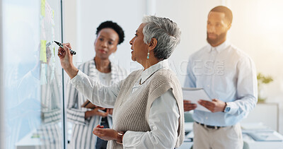 Buy stock photo Mature woman, writing and schedule planning with team on glass board for reminder, project or tasks. CEO, executive or female person taking notes with group for brainstorming or ideas in workplace