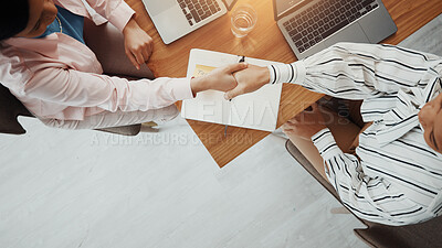Buy stock photo Business people, meeting or above with handshake for deal, introduction or partnership in office. Top view, employees or colleagues shaking hands with laptop or book for b2b or agreement in workplace