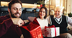 Christmas, gift and man with family on sofa for holiday season, bonding and support. Festive celebration, smile and xmas present with people in living room of home for love, package and relax