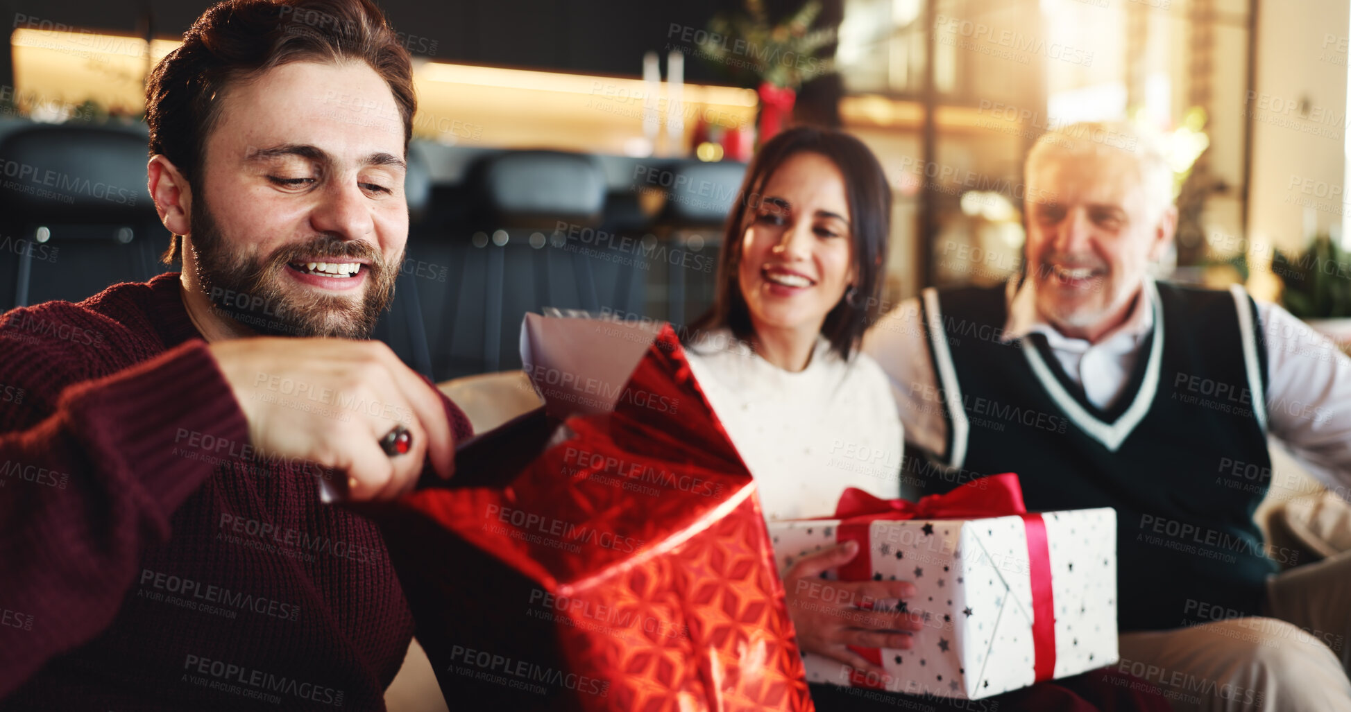 Buy stock photo Christmas, gift and man with family on sofa for holiday season, bonding and support. Festive celebration, smile and xmas present with people in living room of home for love, package and relax