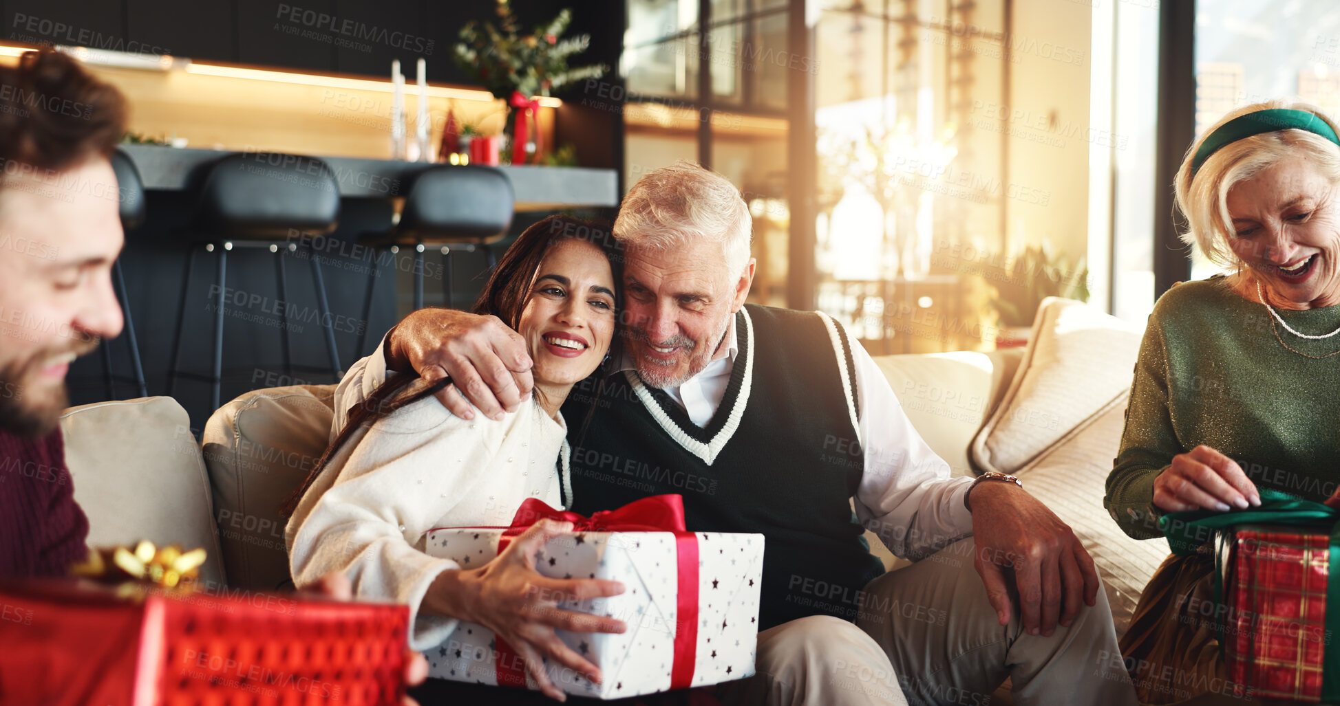Buy stock photo Christmas, gift and hug with family on sofa for holiday season, bonding and support. Festive celebration, smile and xmas present with people in living room of home for love, package and relax