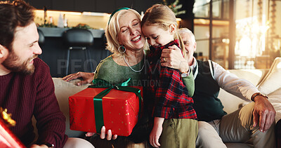 Buy stock photo Christmas, gift and hug with grandmother and child on sofa for holiday season, bonding and support. Festive celebration, smile and present with family in living room of home for love and relax