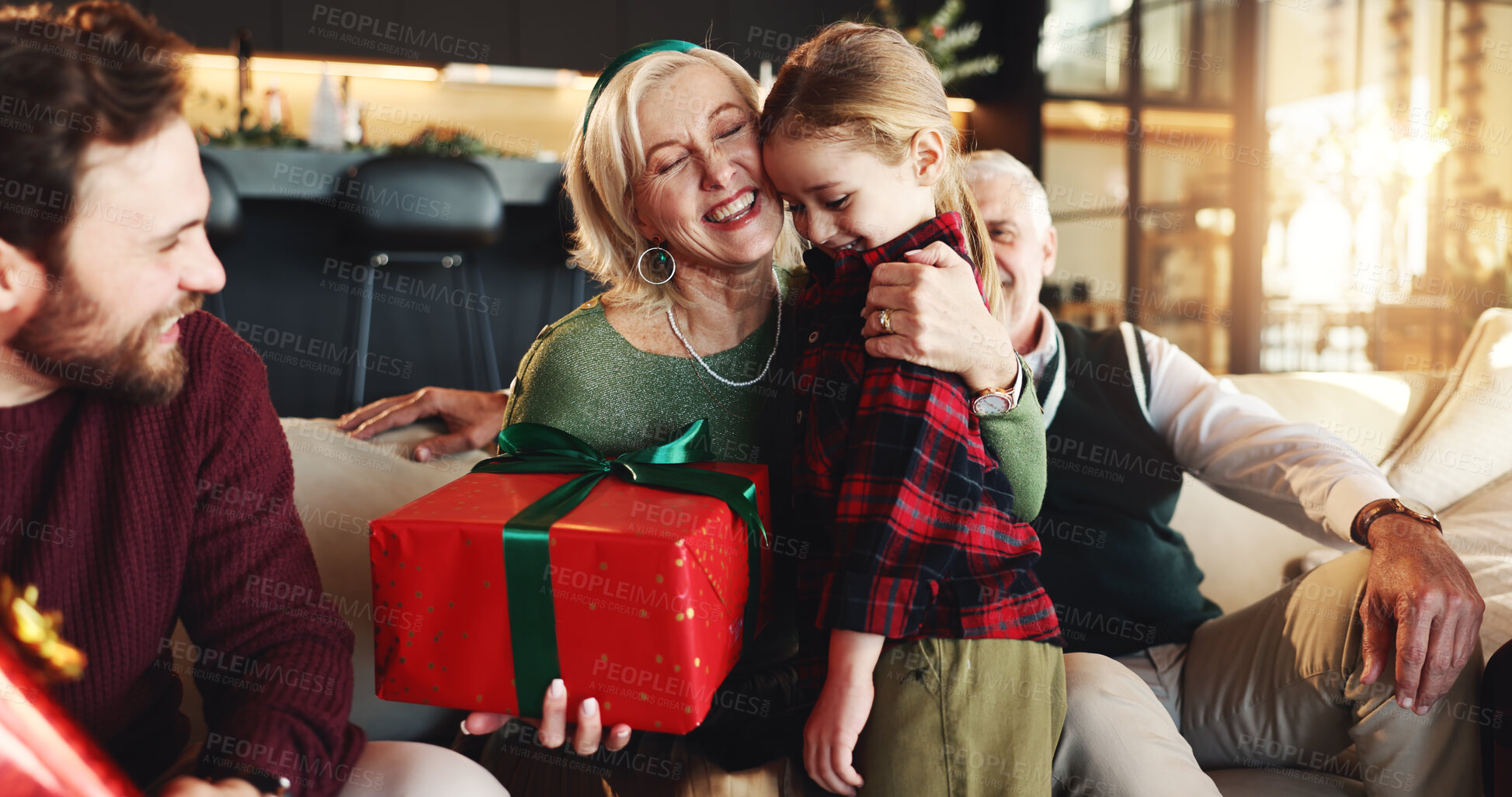 Buy stock photo Christmas, gift and hug with grandmother and child on sofa for holiday season, bonding and support. Festive celebration, smile and present with family in living room of home for love and relax
