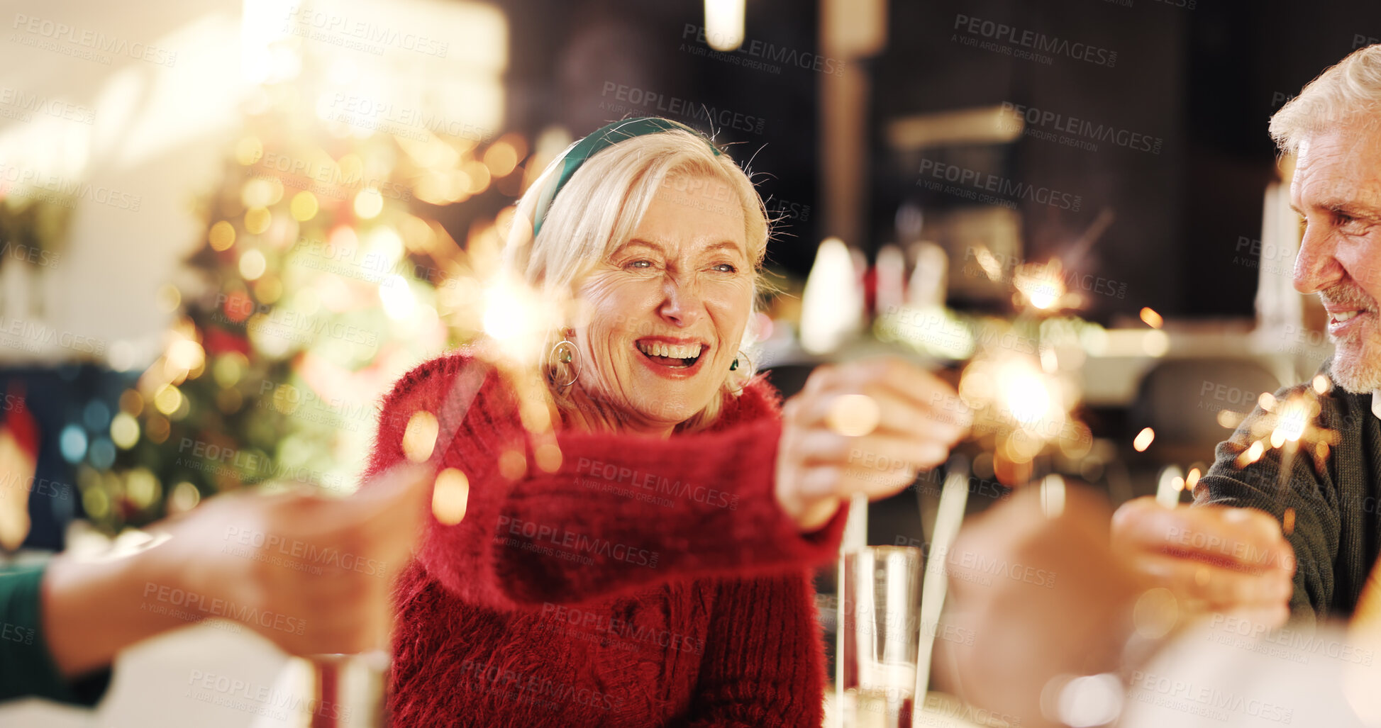 Buy stock photo Christmas, sparkler and party with family in home for celebration, social reunion and festive season. Merry xmas, cheers and mature woman with people in living room for holiday, support and event