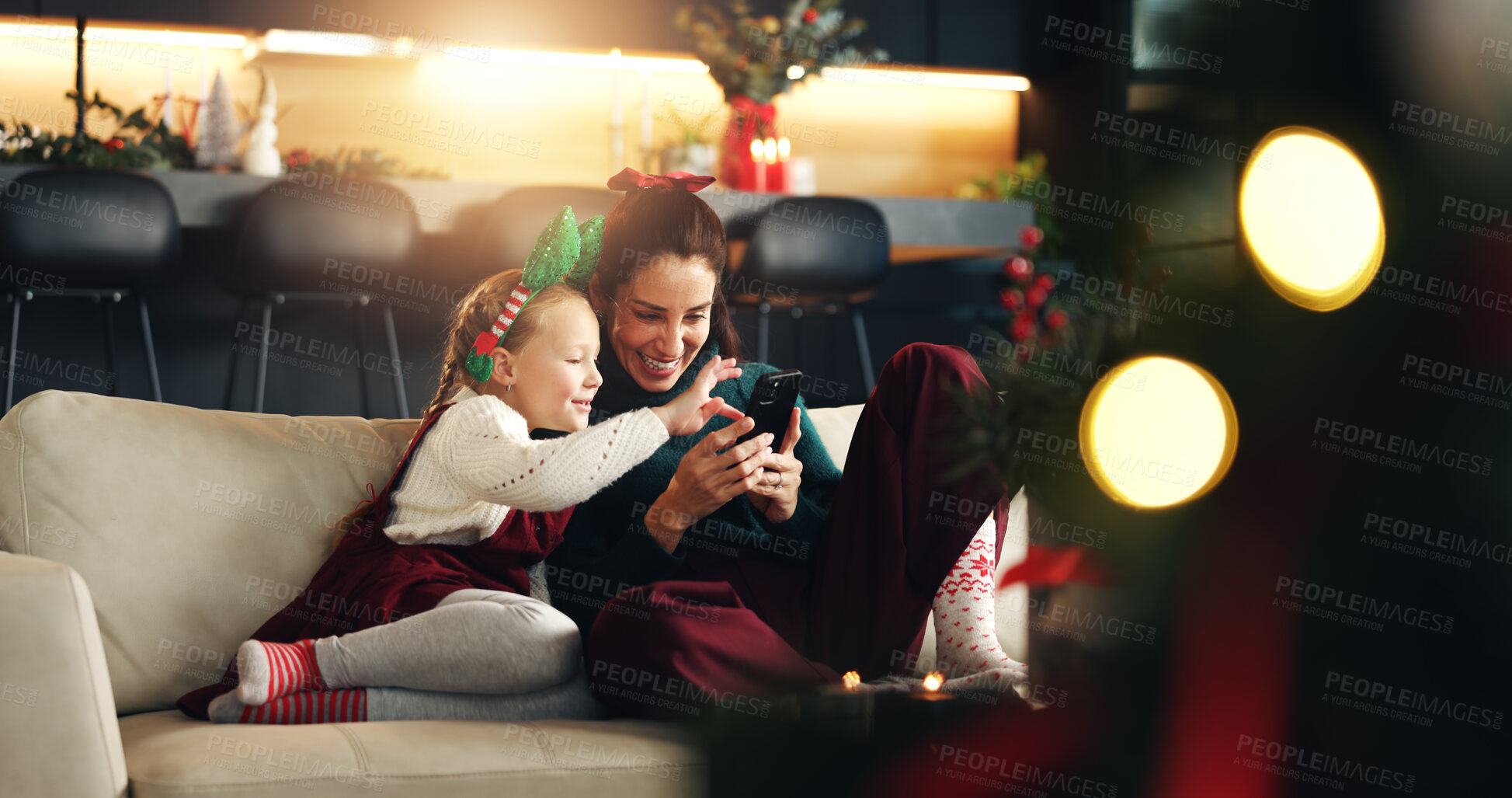 Buy stock photo Christmas, mother and happy girl with phone on sofa for festive season, bonding and family smile. Xmas, daughter and mom with tech in home for social media, holiday memory and together in living room