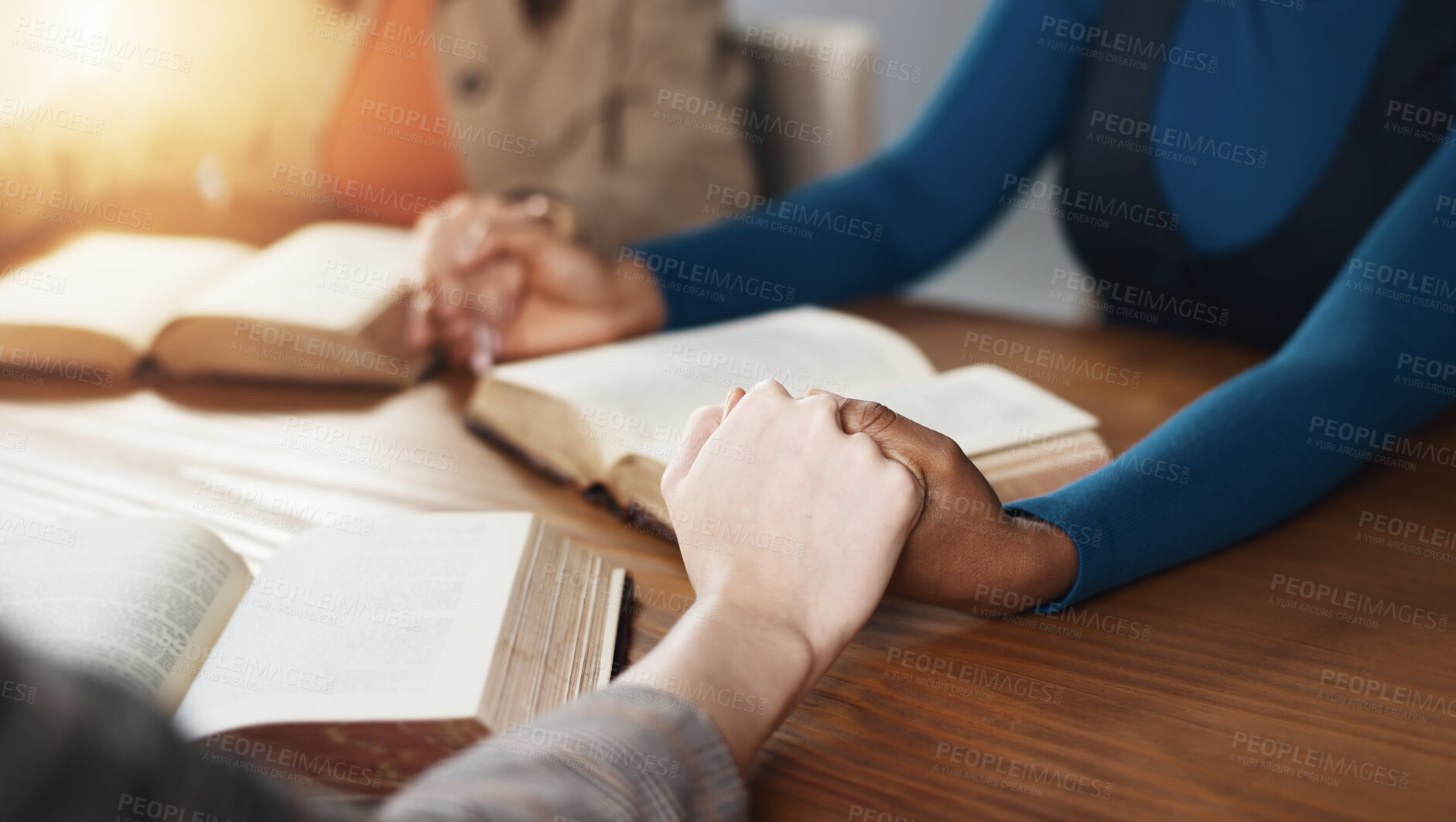 Buy stock photo Hand holding, Bible and people praying with religion, guidance or support with scripture for worship. Christianity, faith and group together by table, book of God and praise with spiritual education
