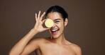 Happy woman, portrait or lemon with skincare for vitamin C or detox on a brown studio background. Face, female person or model with smile or natural organic fruit for citrus acid, health and collagen