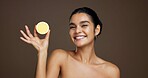 Happy woman, portrait or lemon with vitamin C for detox or skincare on a brown studio background. Face, female person or model with smile or natural organic fruit for citrus acid, health and collagen