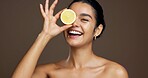 Happy woman, portrait or lemon with vitamin C in studio for skincare detox on a brown background. Face, female person or model with smile or natural organic fruit for citrus acid, health and collagen
