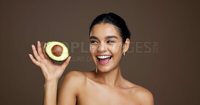 Buy stock photo Woman, avocado and happy in studio for skincare, laugh and sustainable beauty by background. Girl, model and thinking with food for natural wellness, organic fruit and excited for results with glow