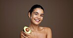 Beauty, woman and portrait with avocado in studio for natural skincare, dermatology or omega 3 on background. Healthy glow, green fruit and sustainable antiaging with clean skin or self care space