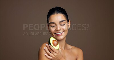 Buy stock photo Skincare, smile and woman with avocado in studio for hydration, natural antioxidants and vitamin c. Mockup, beauty and girl with fruit for hyperpigmentation or anti aging benefits on brown background