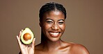 Dermatology, avocado and portrait of black woman in studio with natural, antioxidants or face glow. Happy, beauty and African female person with fruit for moisturizing skincare by brown background.