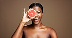 Happy, black woman and portrait with grapefruit in studio for skincare on a brown background. Face, female person or African model with smile or natural organic fruit for vitamin diet or nutrition