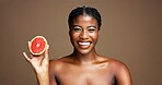 Happy, black woman and portrait with grapefruit for skincare or health on a brown studio background. Face, female person or model with smile or natural organic fruit for vitamin diet or nutrition