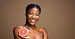 Skincare, happy and portrait of black woman with grapefruit in studio for natural, organic or facial glow. Dermatology, beauty and African person with citrus for face brightening by brown background.