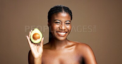 Buy stock photo Beauty, avocado and portrait of black woman in studio with natural, antioxidants or face glow. Happy, skincare and African female person with fruit for moisturizing dermatology by brown background.