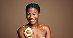 Natural, avocado and portrait of black woman in studio with skincare, antioxidants or face glow. Happy, beauty and African female person with fruit for moisturizing dermatology by brown background.