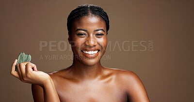 Buy stock photo Beauty, face and gua sha with black woman on studio space for dermatology or wellness. Jade stone, smile and skincare with happy African model on banner to massage or relax skin for antiaging routine