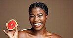Happy, black woman or portrait with grapefruit for skincare or health on a brown studio background. Face, female person or model with smile or natural organic fruit for vitamin C, diet or fiber