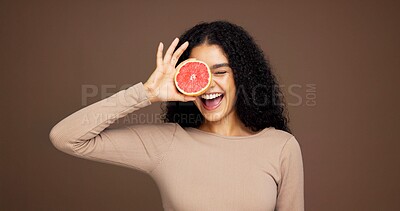 Buy stock photo Happy, woman and grapefruit for skincare in studio for vitamin c, brighten skin and natural detox. Female person, fruit and facial for organic benefits, beauty and exfoliate shine on brown background