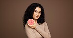 Beauty, woman and smile with grapefruit in studio for skincare benefits, vitamin c or anti aging. Mockup space, girl and happy with fruit on brown background for exfoliation treatment or healthy skin