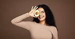 Smile, woman and avocado for skincare in studio for vitamin c, brighten skin and natural detox. Female person, fruit and facial with organic benefits, beauty and hydration results on brown background
