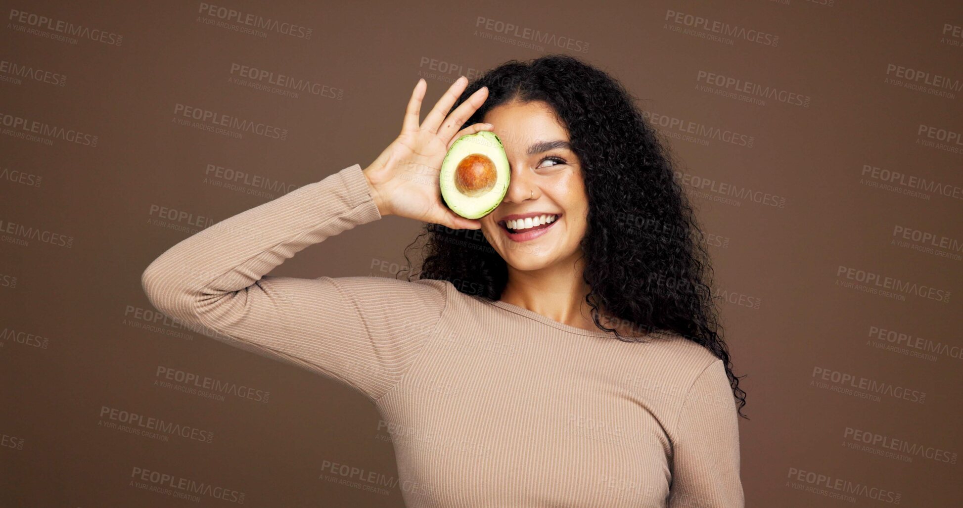 Buy stock photo Smile, woman and avocado for skincare in studio for vitamin c, brighten skin and natural detox. Female person, fruit and facial with organic benefits, beauty and hydration results on brown background