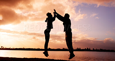 Buy stock photo Silhouette, couple and jump with high five at river for winning, success or achievement together. Excited, man and woman in sunset with touch for teamwork, accomplishment or fitness goals at lake