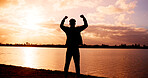 Silhouette, man or back view with fist pump at river for winning, achievement or conquer in sunset. Active, male person or celebration with success for accomplishment, done or freedom at pond or lake