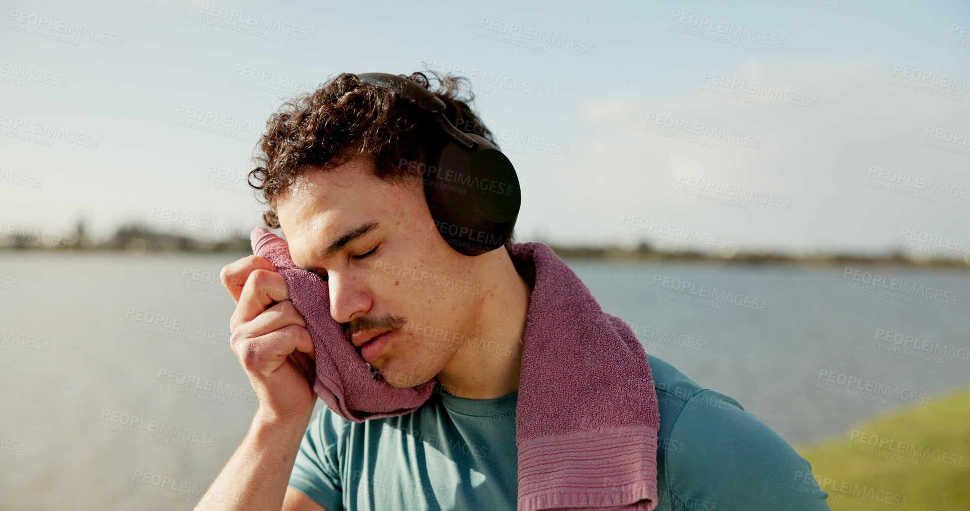 Buy stock photo Towel, sweating or tired man in lake with headphones for outdoor training, workout or exercise. Exhausted, recovery and sports athlete on break for streaming radio, music audio and fitness podcast