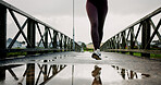 Legs, running and woman with exercise on bridge for pace training, winter workout or dedication. Fitness, puddle and person with cardio outdoor for race endurance, marathon competition and resilience