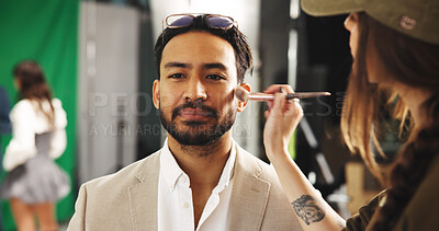 Buy stock photo Celebrity, man and artist apply makeup behind the scenes to prepare for movie on set. Brush, application and stylist in production studio with actor for beauty, facial touch up or cosmetics for film