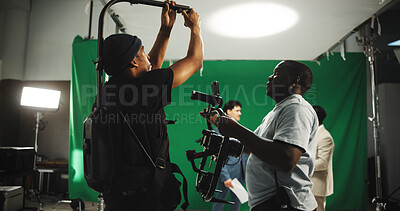 Help, equipment and men with camera on set for adjustment, stabilizing tech and filming. Behind the scenes, videography and person with operator for shooting, production and filmmaking in studio