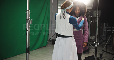 Buy stock photo Creative, women and fashion stylist on set, preparation and fixing clothes for photoshoot and cover. Serious, model and adjustment to outfit for video shoot, people and crew for production or art
