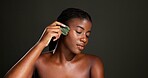 Gua sha, skincare and black woman in studio for beauty, smooth skin and facial massage. Dermatology, space and person with tools for glow, face treatment and lymphatic drainage on dark background