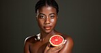 Black woman, portrait and skincare with grapefruit in studio for beauty on a dark background. Face, female person or African model with natural organic fruit for vitamin C or body health on space