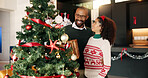 Happy, Christmas tree and couple in home with decoration for bonding, tradition and holiday. December, love and African man and woman hanging ornaments for celebration, festive season and xmas